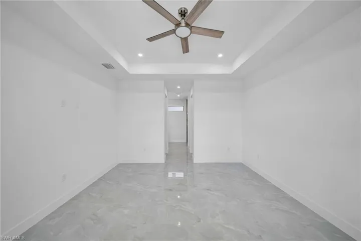 Unfurnished room featuring a raised ceiling, a ceiling fan, and recessed lighting