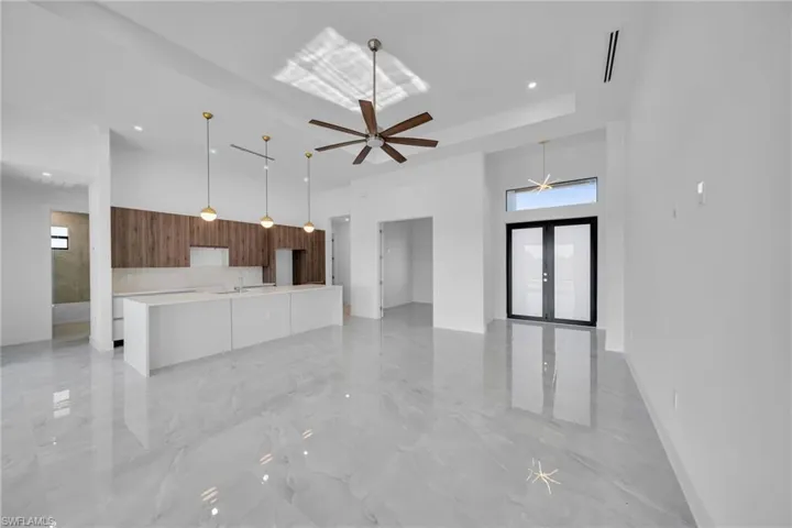Unfurnished living room with french doors, a high ceiling, light marble finish floors, ceiling fan, and recessed lighting