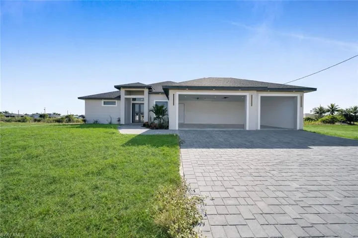 Prairie-style house with a front lawn, decorative driveway, and a garage