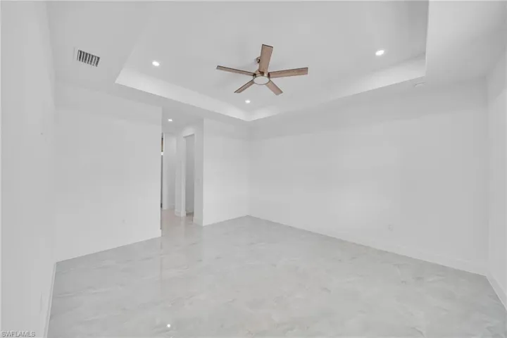 Spare room featuring ceiling fan, finished concrete flooring, a tray ceiling, and recessed lighting