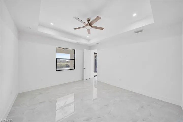 Unfurnished bedroom with ceiling fan, recessed lighting, and a raised ceiling