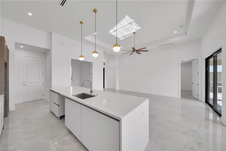 Kitchen with modern cabinets, white cabinets, pendant lighting, a kitchen island with sink, and open floor plan