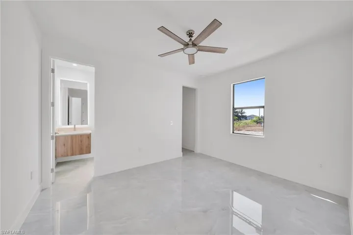 Unfurnished bedroom with concrete flooring, ceiling fan, and ensuite bathroom