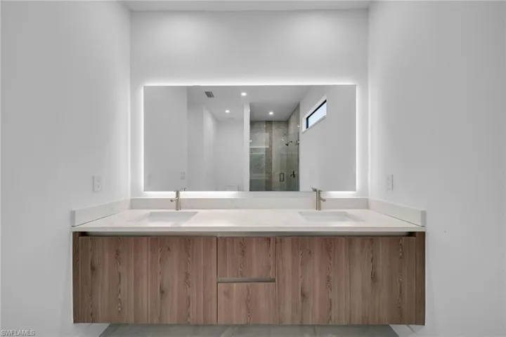 Bathroom with double vanity, a shower stall, and recessed lighting