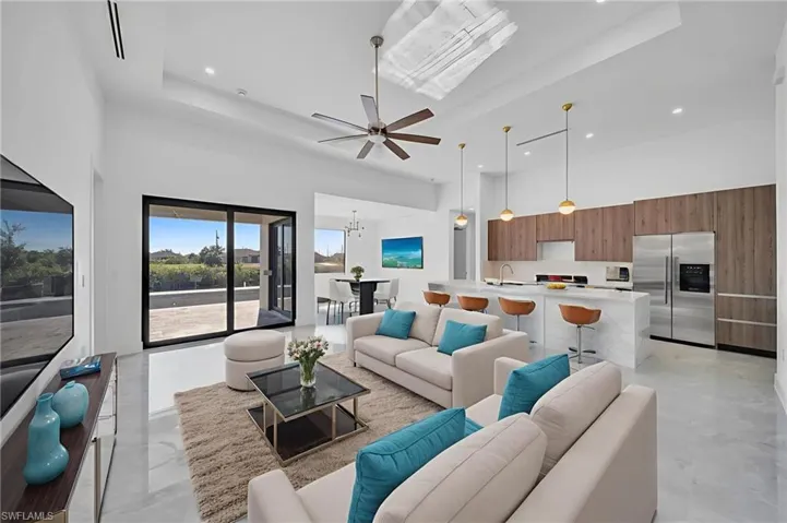 Living room featuring a high tray ceiling, ceiling fan, and a chandelier