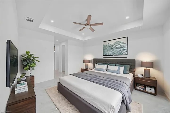 Bedroom featuring ceiling fan, recessed lighting, a raised ceiling, and finished concrete flooring