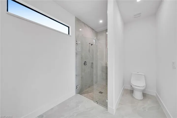 Bathroom with a marble finish shower, recessed lighting, and marble finish flooring