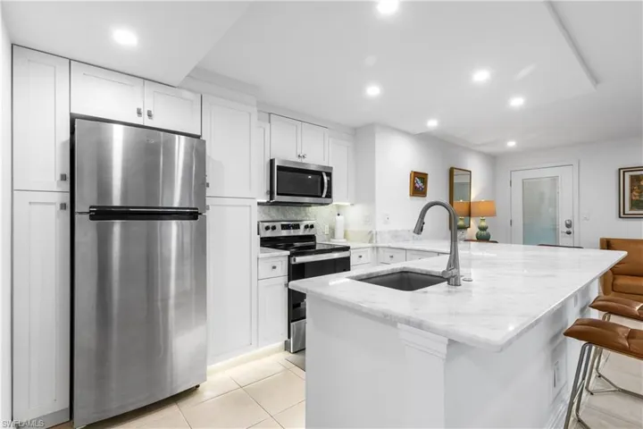 Kitchen has marble countertops, undercounter sink, under cabinet lighting along with stainless steel appliances; refrigerator, stove, microwave, dishwasher, and disposal.