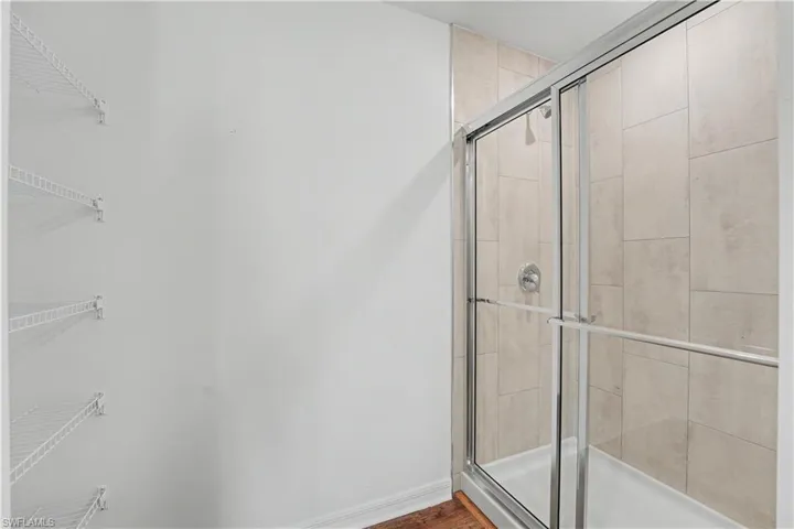 Walk-in shower featuring a sliding glass door, neutral-toned tile surround, and a chrome shower fixture