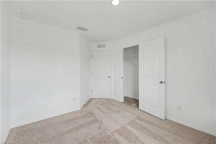 Carpeted interior room featuring white walls, a white ceiling, recessed lighting, two panel doors, and a built-in closet with shelving and a hanging rod