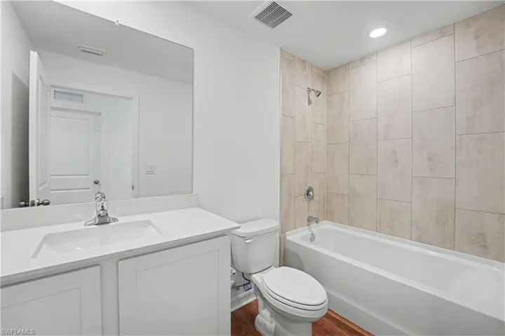 Bathroom featuring a white vanity with an integrated sink, polished chrome faucet, and a large wall mirror