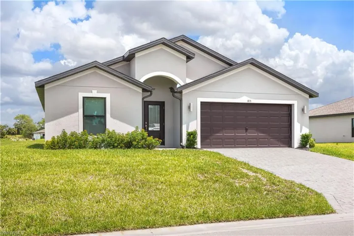 Contemporary stucco exterior with dark gray roofing, a two-car garage, and a paver driveway