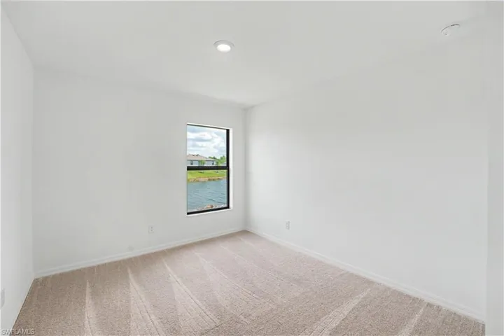 Bright interior room featuring a window overlooking a water feature and distant residences