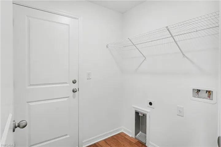 Dedicated laundry area featuring wood-finish flooring and white baseboards