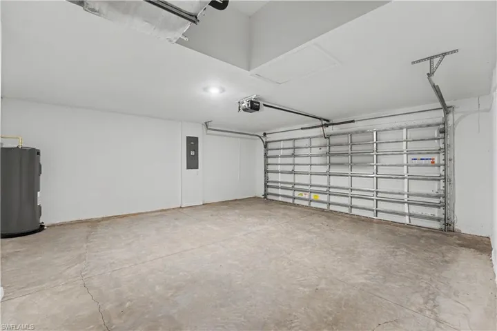 Spacious garage featuring a concrete floor, white painted walls, and a metal roll-up garage door with an automatic opener
