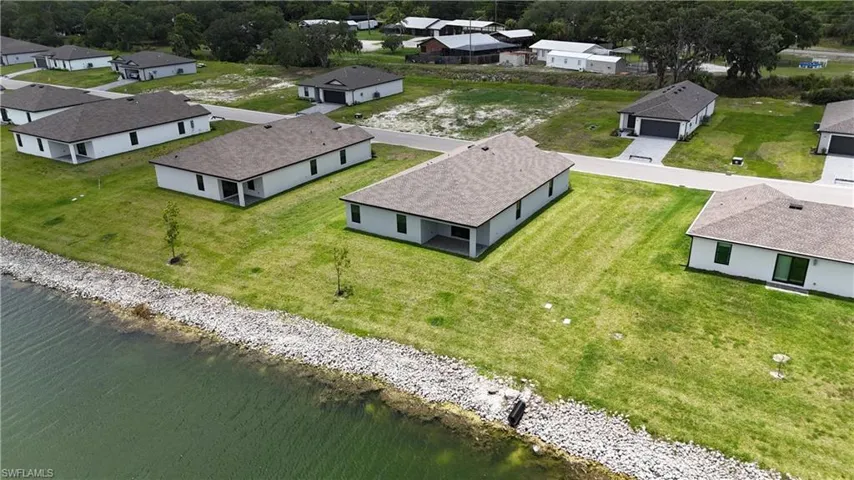 Modern single-story residence featuring a covered patio and a large grassy yard bordering a body of water