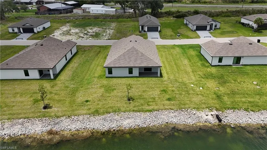 Rear exterior of a single-story residence featuring a covered patio overlooking a body of water