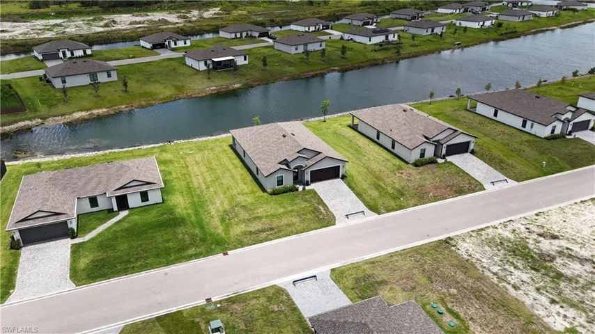 Waterfront property featuring a paver driveway, an attached garage, and a gabled roofline