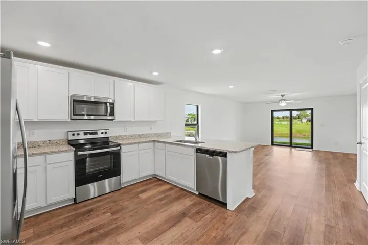 Modern kitchen featuring white cabinetry, granite-finish countertops, and stainless-steel appliances