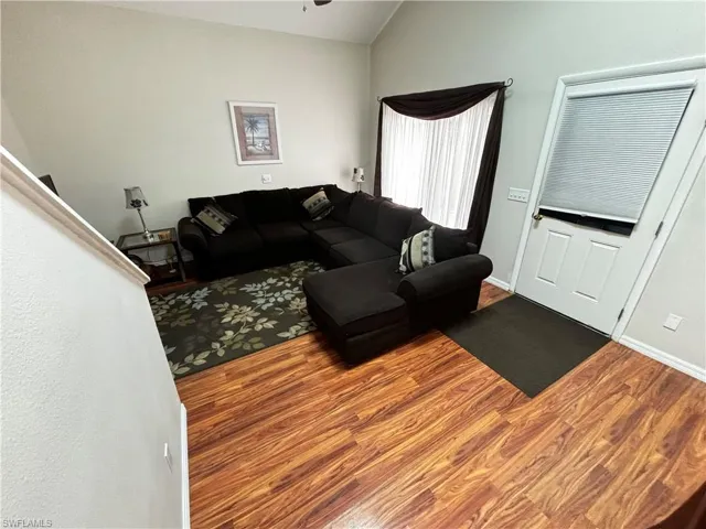 Living area featuring wood finished floors, vaulted ceiling, and a ceiling fan