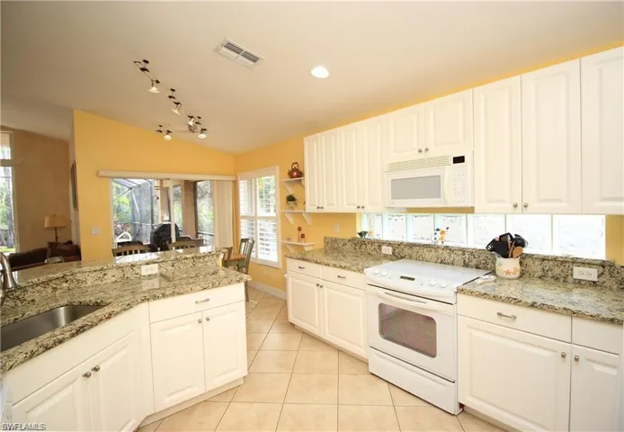 Kitchen featuring white appliances, white cabinetry, and sink