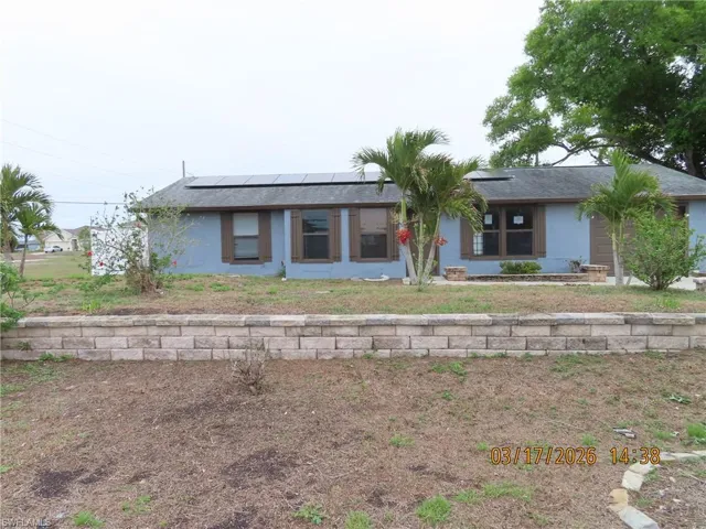 Back of house with roof mounted solar panels, stucco siding, and roof with shingles
