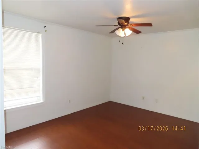 Unfurnished room with dark wood-style floors, ceiling fan, and ornamental molding