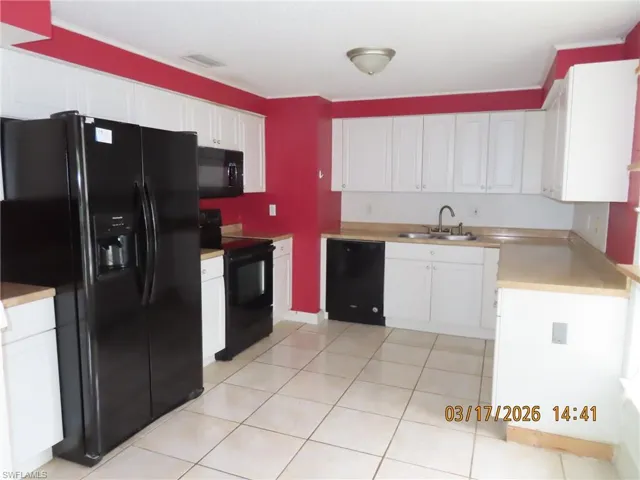Kitchen featuring black appliances, white cabinetry, and light countertops