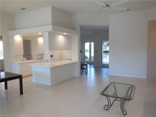 Kitchen featuring baseboards, a high ceiling, light countertops, and white cabinets