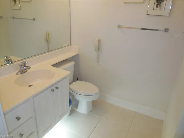 Bathroom featuring toilet, tile patterned flooring, baseboards, and vanity