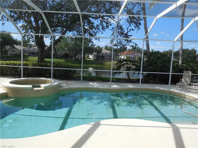 View of pool with a water view, a patio area, a pool with connected hot tub, and glass enclosure
