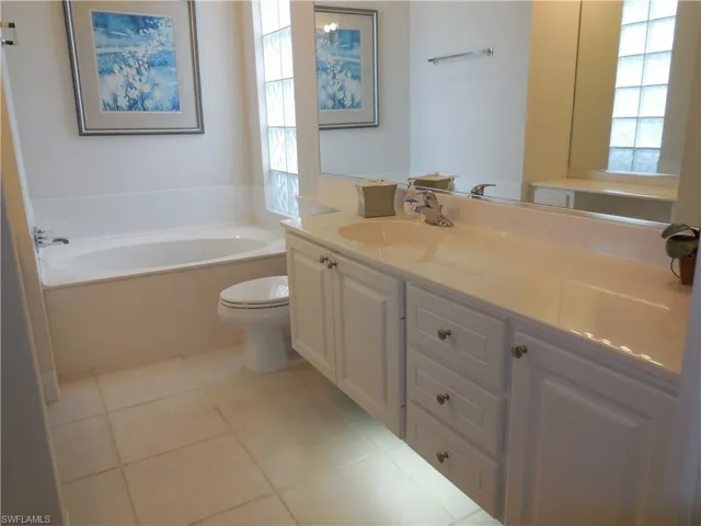 Full bathroom featuring toilet, a garden tub, vanity, and tile patterned flooring