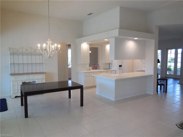 Kitchen featuring light countertops, white cabinetry, plenty of natural light, and a towering ceiling