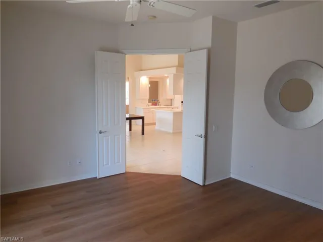 Empty room with visible vents, ceiling fan, wood finished floors, and baseboards