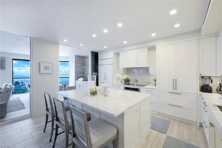 Kitchen with a center island, tasteful backsplash, recessed lighting, light stone counters, and white cabinets