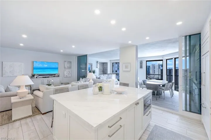 Kitchen featuring open floor plan, a center island, light stone countertops, white cabinetry, and recessed lighting