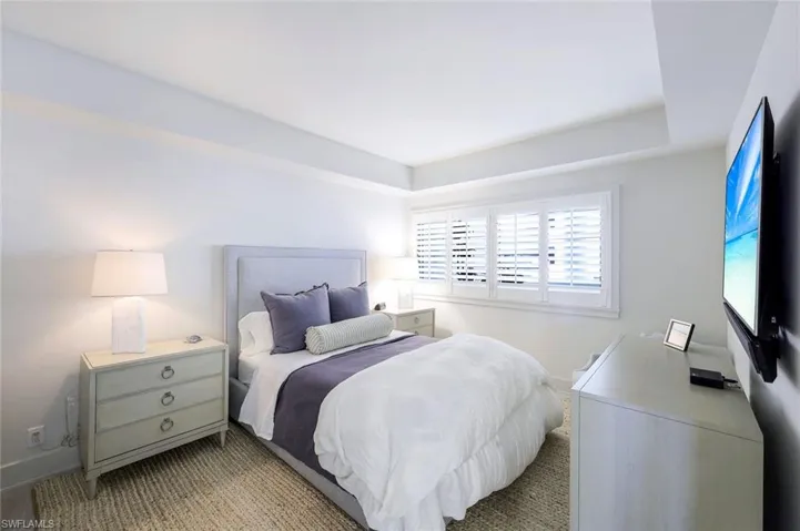 Bedroom with light colored carpet and a tray ceiling
