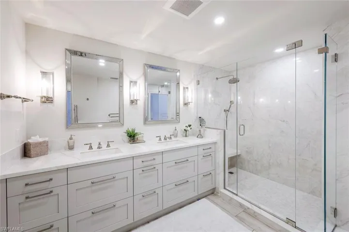 Full bathroom featuring double vanity and a shower stall