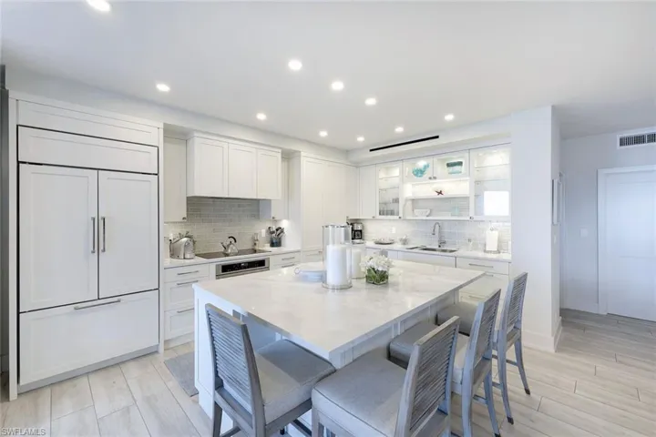 Kitchen featuring paneled built in fridge, backsplash, a breakfast bar, white cabinetry, and a center island