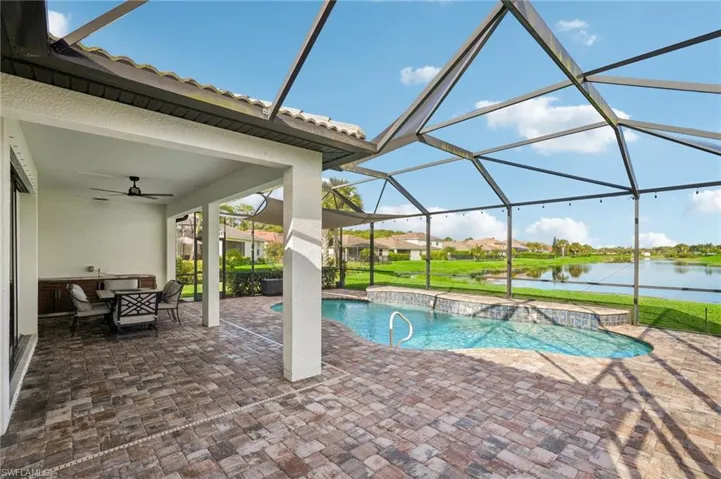 View of pool featuring a screened lanai area, a lawn, and a water view