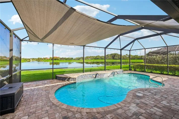 View of pool featuring a screened lanai area, a lawn, and a water view