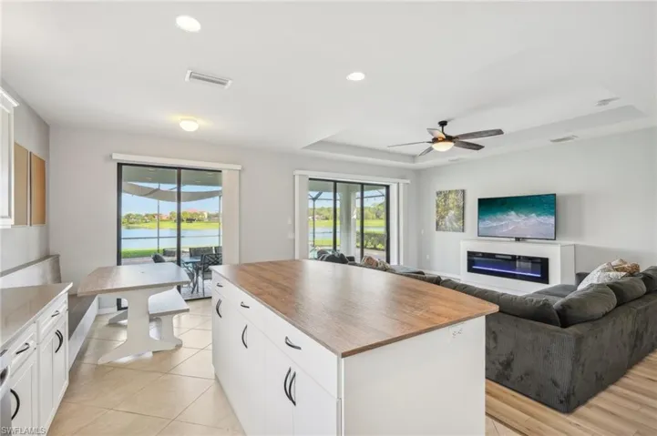 Kitchen featuring white cabinets, light tile flooring, stainless steel appliances, sink and center island