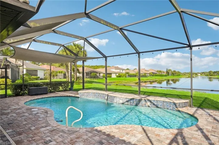 View of pool featuring a screened lanai area, a lawn, and a water view