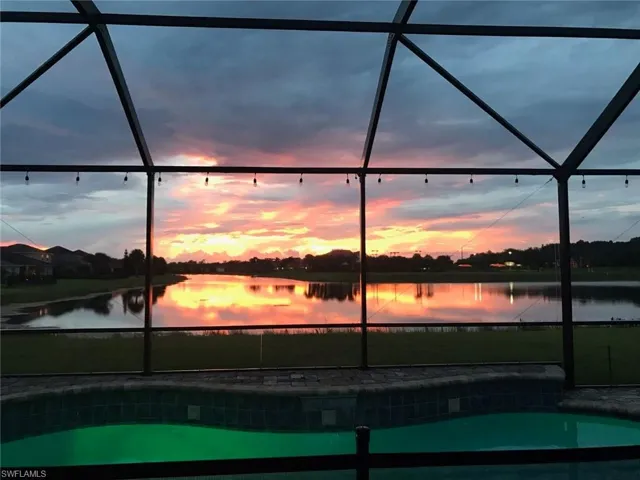 Pool at dusk featuring a water view and a lanai