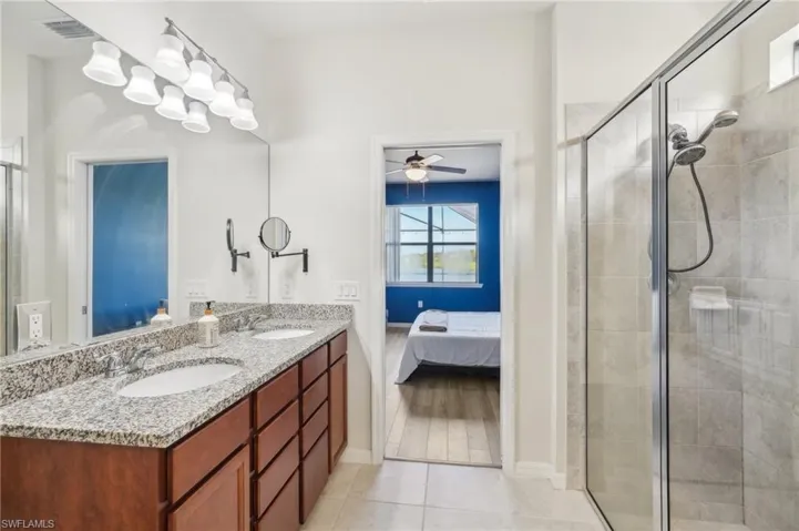 Master Suite Bathroom featuring toilet, tile flooring, walk in shower, dual sink and a walk-in closet