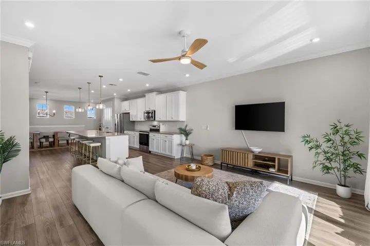Living room with ornamental molding, a ceiling fan, dark wood-type flooring, recessed lighting, and a chandelier