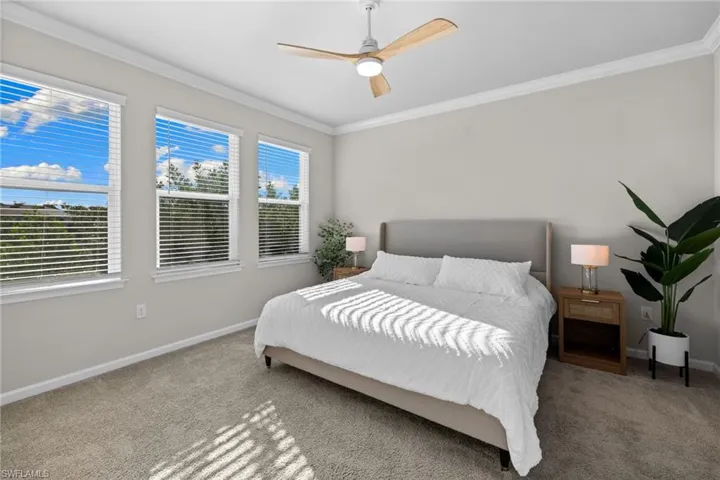 Carpeted bedroom with ornamental molding and a ceiling fan