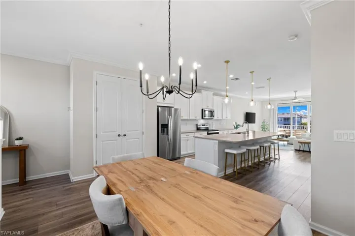 Dining area featuring dark wood-style floors, a chandelier, recessed lighting, ornamental molding, and a ceiling fan