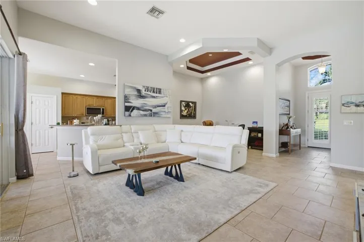 Living room with recessed lighting, arched walkways, and a high ceiling