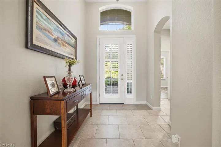 Entryway featuring arched walkways, a textured wall, and light tile patterned floors